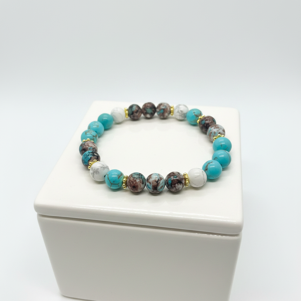 Turquoise, earth stone and white howlite beaded bracelet with gold accents displayed on a white jewelry box